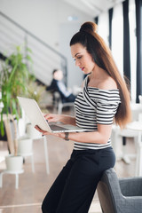 Happy smiling businesswoman leaning on the office desk and using pc tablet.