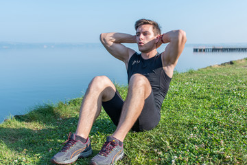 Fitness training. Young sportsman doing abdominal crunches outdoors.