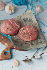 Organic raw ground beef wrapped in strips of bacon.