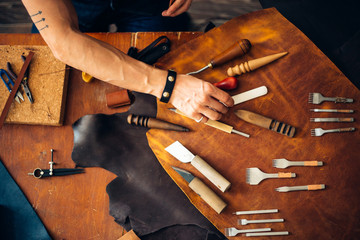 Crafting tools on natural cow leather in the tailoring workshop. Top view.