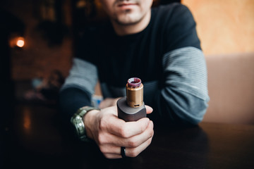 Close-up of electronic cigarette. The man smiles and smokes vape. The concept of refusal of tobacco. Vaping