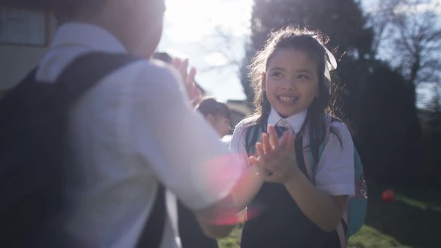  Happy young children playing pat a cake outdoors in school playground
