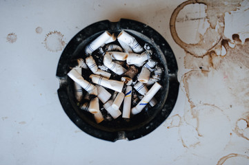 Ashtray with cigarette butts on the table.