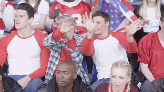  Crowd of spectators watching sports game in stadium waving to camera