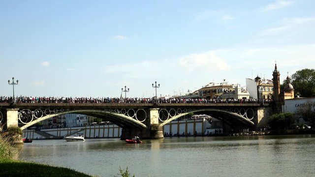 SEVILLE, SPAIN - APRIL 14: People and nazarenes crossing the triana bridge. April 14, 2017 in Seville, Spain.