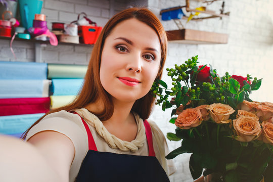young girl working in a flower shop, Floristry makes selfie photo with a bouquet of flowers