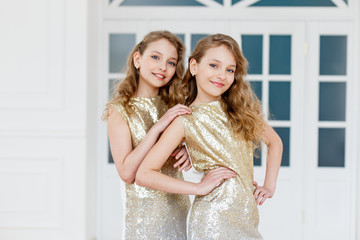 Beautiful twin sisters wearing fashionable golden dresses