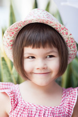 Happy asian smiling child with hat play in a garden 