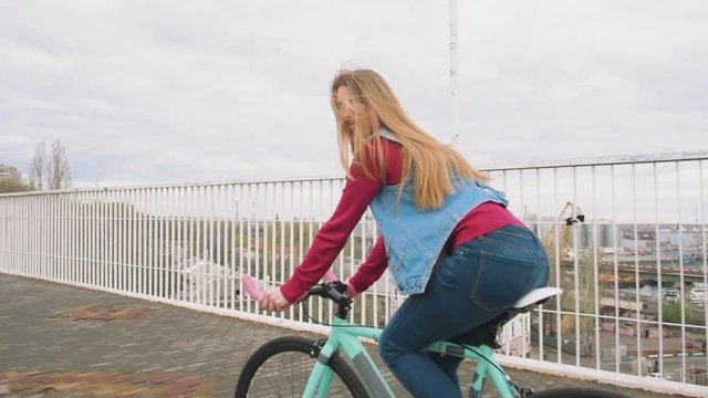 A young hipster girl riding a fixed gear bike at city centre, slow motion