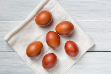 Colorful brown easter eggs on cloth and white wooden table