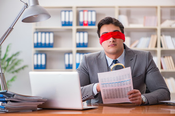 Blindfold businessman sitting at desk in office