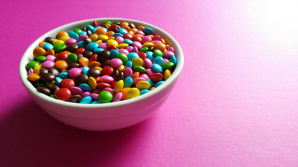 Pot with colorful confetti on pink background
