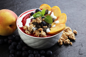 breakfast smoothie bowl with blueberries, peach and granola
