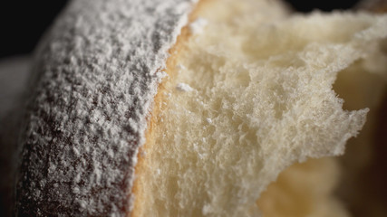 Delicious croissant with powdered sugar on black background