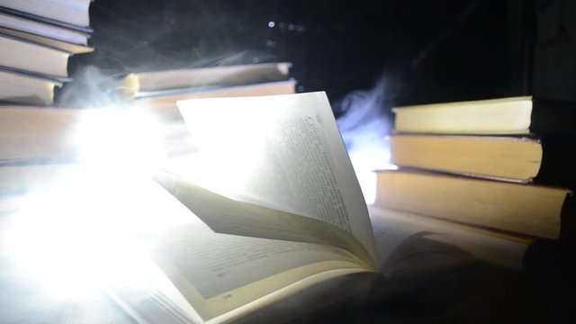 Many old books in a stack. Knoledge concept. Books on a dark background with smoke elements. Bewitched book in center. Glasswatch