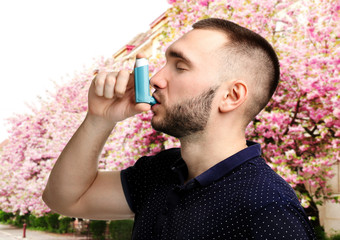 Young man using asthma inhaler outdoor