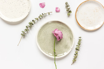 Obraz na płótnie Canvas rose, eucalyptus and plates in spring design white background top view mockup