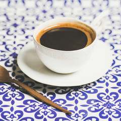 Cup of black Turkish or Eastern style coffee over oriental bright motley Moroccan patterned background, selective focus