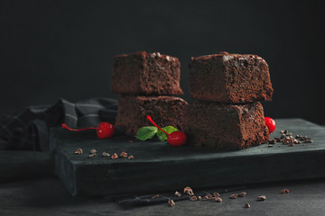 Wooden board with delicious cocoa brownies on table