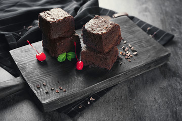 Wooden board with delicious cocoa brownies on table