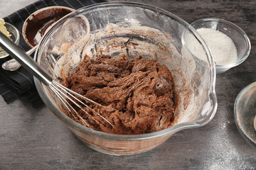 Bowl with dough for cooking cocoa brownies on table