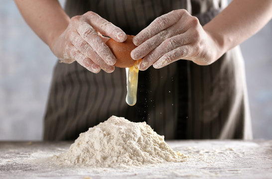 Woman making dough for ravioli on table