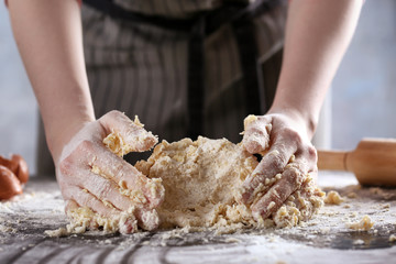 Woman making dough for ravioli on table