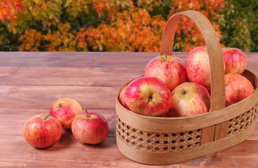 Basket with lying in her red apples on a wooden surface.