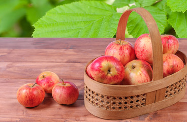 Basket with lying in her red apples on a wooden surface.