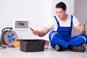Young electrician working on socket at home
