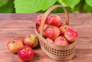 Basket with apples on a wooden background.