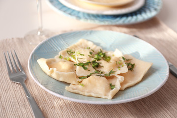 Plate with delicious ravioli on table