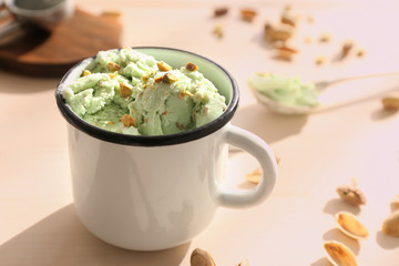 Pistachio ice cream with chopped nuts in mug on wooden table