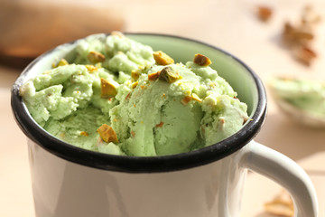 Pistachio ice cream with chopped nuts in mug, closeup