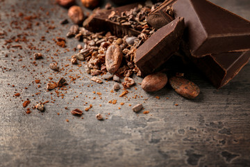 Cocoa beans and pieces of chocolate on table