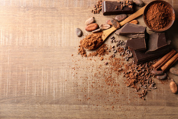 Composition with cocoa powder and pieces of chocolate on wooden background - obrazy, fototapety, plakaty
