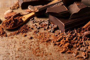 Composition with cocoa powder and pieces of chocolate on wooden background