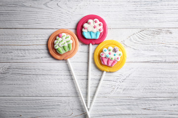 Tasty colorful lollipops on wooden background