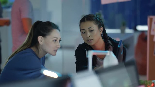  Young game designers looking at computer screen & discussing interface design