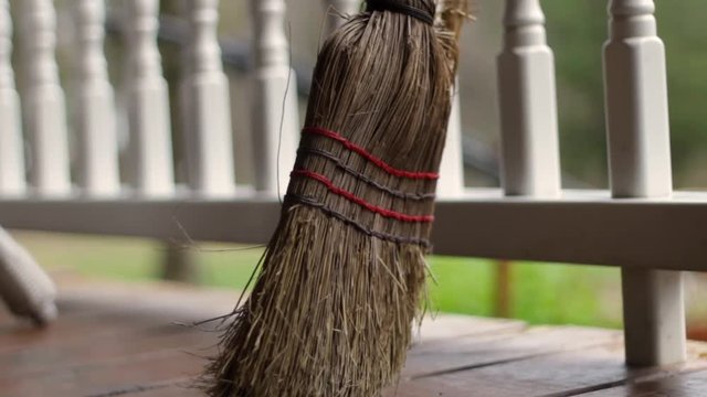 Camera slides past old destroyed broom leaning on porch fence