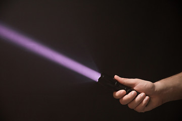 Black ultraviolet flashlight in male's hand isolated on black background - obrazy, fototapety, plakaty