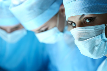 Three surgeons at work operating in surgical theatre