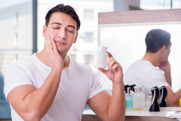 Young handsome man applying face cream