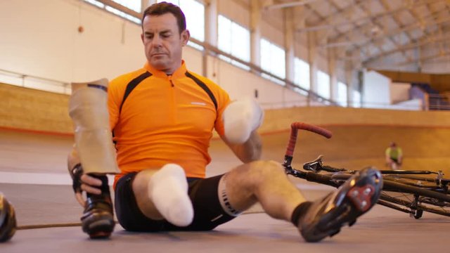  Man with prosthetic leg at cycling track attaches limb and prepares to train