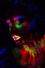 Beautiful extraterrestrial model woman in neon light. It is portrait of beautiful model with fluorescent make-up, Art design of female posing in UV with colorful make up. Isolated on black background