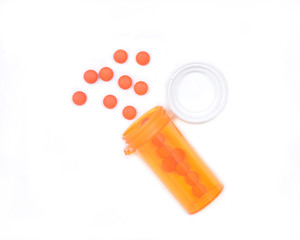 Orange pills in plastic bottle with a cap isolated on white background
