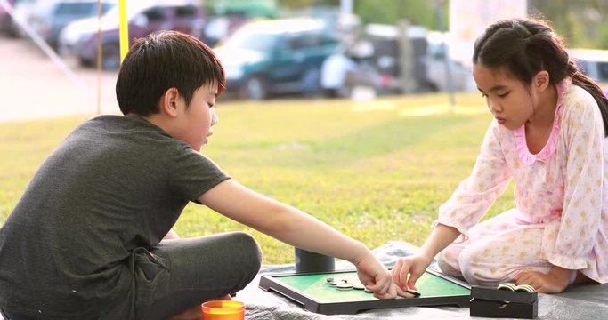 Happy asian boy and girl playing board game in camping area