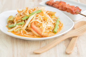 Papaya salad in a white plate on a wooden table,Local thai food