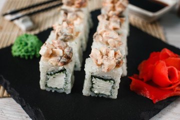 Fresh appetizing set of Japanese sushi rolls served on black slate. with wasabi and ginger. Healthy food, traditional Asian seafood.