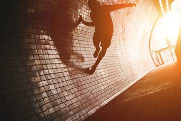 Silhouette of man running on the wall in the dark tunnel. Intentional extremely dark colors, little motion blur